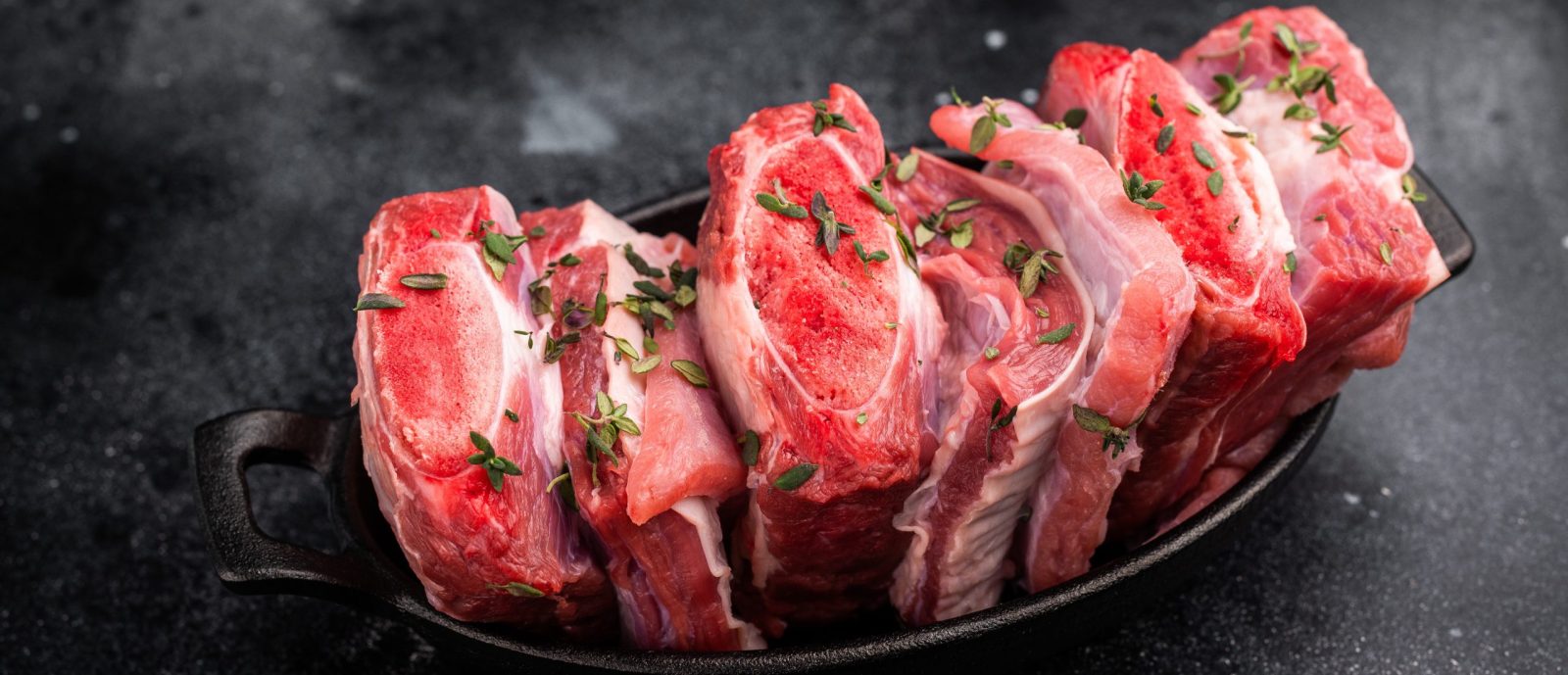 Raw Veal Short Ribs, fresh meat with thyme. black background. top view.